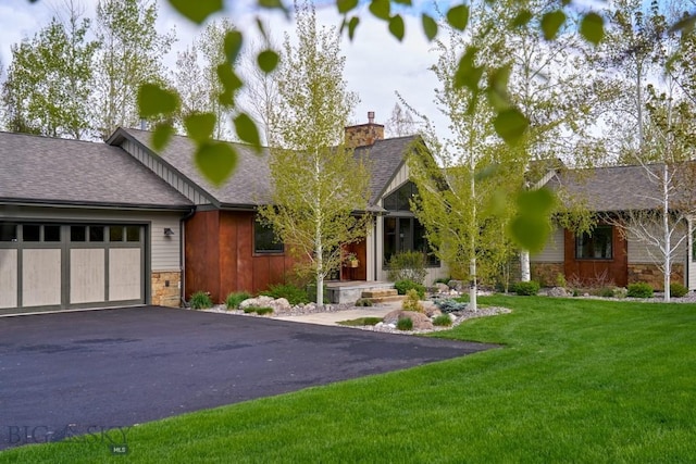 65 Triple Tree Ln, Bozeman, MT 59715 - view of front of property with stone siding, asphalt driveway, a chimney, a garage, and a front yard