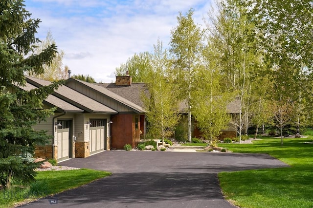 65 Triple Tree Ln, Bozeman, MT 59715 - view of front of house featuring driveway, a chimney, a garage, a front yard, and stone siding