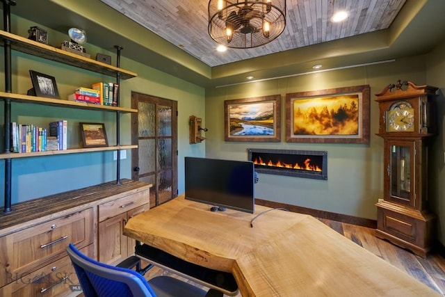 65 Triple Tree Ln, Bozeman, MT 59715 - home office featuring a tray ceiling, wooden ceiling, a lit fireplace, wood finished floors, and baseboards