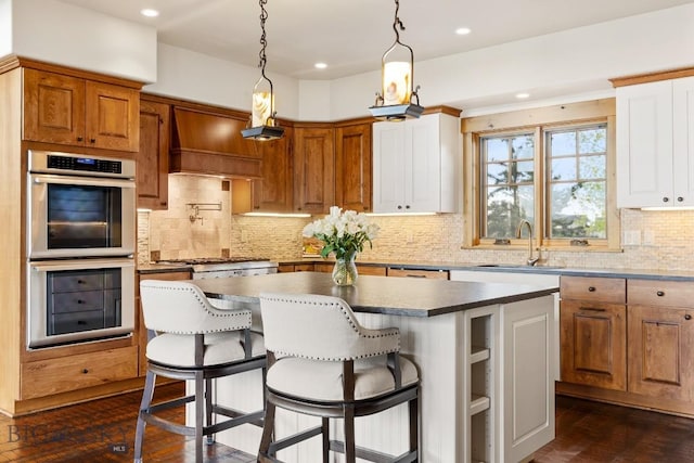 171 Brave Heart Loop, Bozeman, MT 59718 - kitchen featuring appliances with stainless steel finishes, a sink, a kitchen island, backsplash, and dark wood-style flooring
