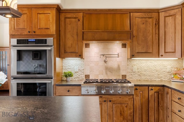 171 Brave Heart Loop, Bozeman, MT 59718 - kitchen with stainless steel appliances, dark countertops, and brown cabinetry