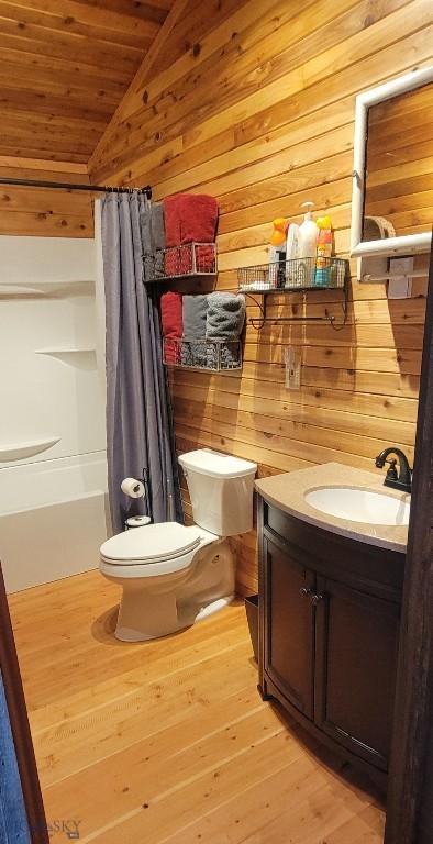 747 Upper Ruby Rd, Alder, MT 59755 - full bathroom with toilet, vanity, wooden walls, wood finished floors, and shower / tub combo