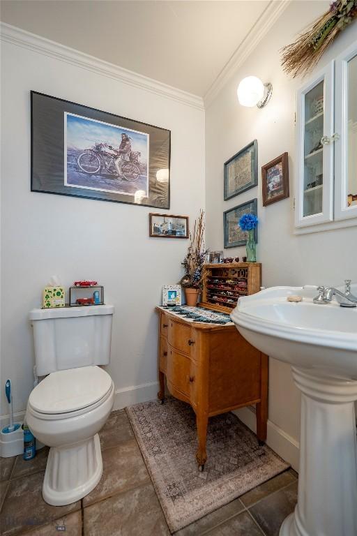 207 2nd St E, Clyde Park, MT 59018 - bathroom featuring toilet, ornamental molding, baseboards, and tile patterned flooring