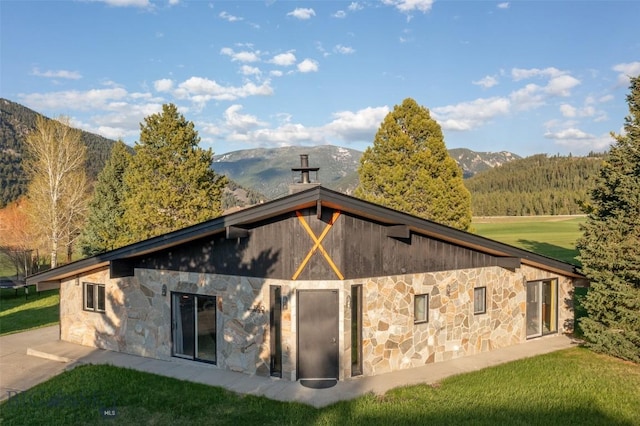 1930 Yellowtail, Big Sky, MT 59716 - rear view of property featuring stone siding, a mountain view, and a yard