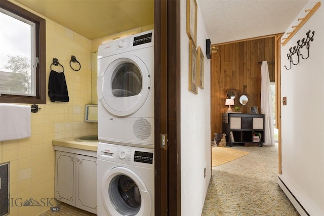 1930 Yellowtail, Big Sky, MT 59716 - laundry room featuring baseboard heating, stacked washer / dryer, wood walls, light colored carpet, and tile walls