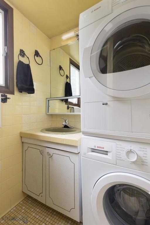 1930 Yellowtail, Big Sky, MT 59716 - laundry area with stacked washing machine and dryer, light tile patterned floors, and tile walls