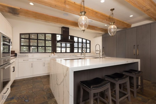 45 Cutthroat Trout, Big Sky, MT 59716 - kitchen with beamed ceiling, island range hood, stone tile flooring, a sink, and light stone counters
