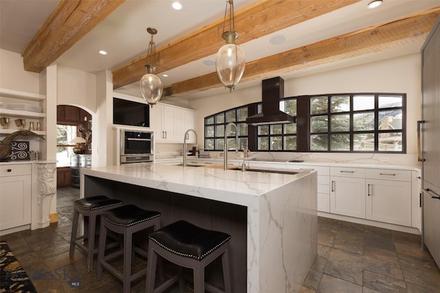 45 Cutthroat Trout, Big Sky, MT 59716 - kitchen with island exhaust hood, beam ceiling, a sink, light stone countertops, and white cabinetry