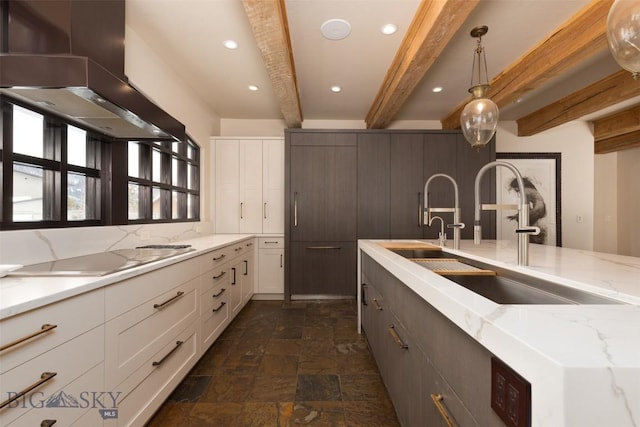 45 Cutthroat Trout, Big Sky, MT 59716 - kitchen with wall chimney range hood, stovetop, beam ceiling, dark stone finish flooring, and white cabinetry