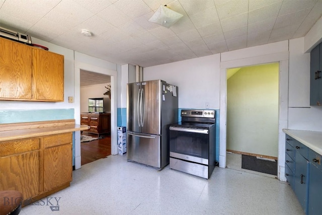 411 W Railroad Ave N, Manhattan, MT 59741 - kitchen with stainless steel appliances, light countertops, brown cabinetry, and dark aggregate flooring