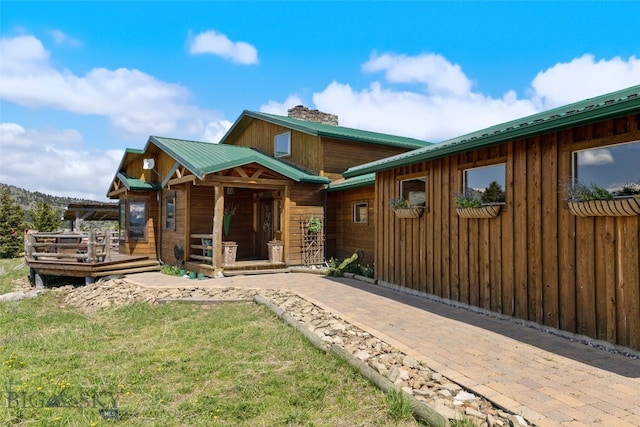 125 Rocky Mountain Mdws, Bozeman, MT 59715 - view of front facade featuring a chimney, a wooden deck, metal roof, and a front yard