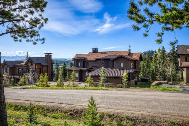 102 Outlook Trl, Big Sky, MT 59716 - view of front of home with stone siding, a standing seam roof, a chimney, and metal roof