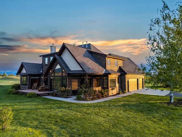 306 Glenbrook Ln, Belgrade, MT 59714 - back of property at dusk with a lawn, driveway, and roof with shingles