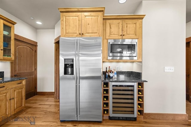 306 Glenbrook Ln, Belgrade, MT 59714 - kitchen featuring stainless steel appliances, beverage cooler, light wood-style flooring, dark stone counters, and glass insert cabinets