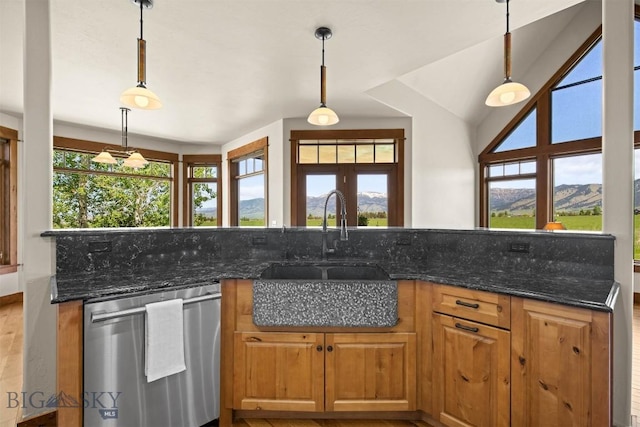 306 Glenbrook Ln, Belgrade, MT 59714 - kitchen with stainless steel dishwasher, a sink, brown cabinets, dark stone countertops, and decorative light fixtures