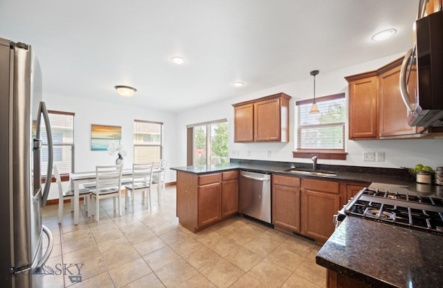4068 Opal St, Bozeman, MT 59718 - kitchen featuring stainless steel appliances, a sink, a peninsula, brown cabinets, and pendant lighting