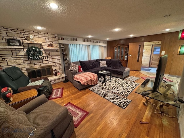 2301 Banks Ave, Butte, MT 59701 - living room with a textured ceiling, hardwood / wood-style floors, a stone fireplace, recessed lighting, and wooden walls