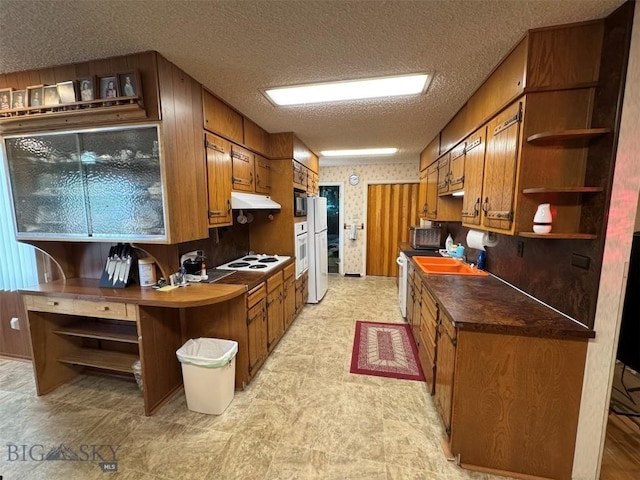 2301 Banks Ave, Butte, MT 59701 - kitchen featuring open shelves, under cabinet range hood, brown cabinets, white appliances, and a textured ceiling