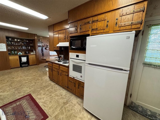 2301 Banks Ave, Butte, MT 59701 - kitchen with white appliances, brown cabinets, under cabinet range hood, a textured ceiling, and wooden walls