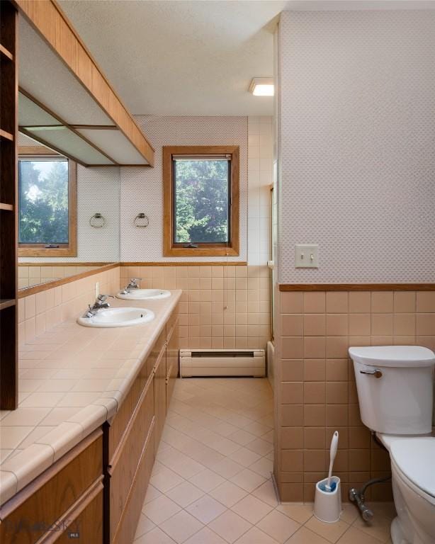 1524 S Grand, Bozeman, MT 59715 - bathroom featuring a baseboard radiator, tile walls, toilet, tile patterned flooring, and wallpapered walls