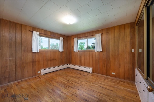 1524 S Grand, Bozeman, MT 59715 - empty room with light wood-type flooring, wood walls, and a baseboard heating unit
