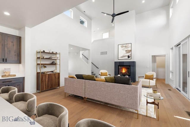 4149 Annie St, Bozeman, MT 59718 - living room featuring a towering ceiling, a ceiling fan, light wood-type flooring, a tile fireplace, and stairs