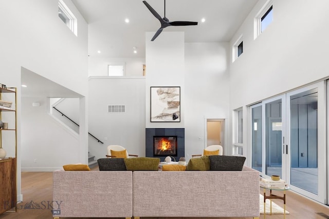 4149 Annie St, Bozeman, MT 59718 - living room featuring a towering ceiling, a tile fireplace, a ceiling fan, wood finished floors, and stairway