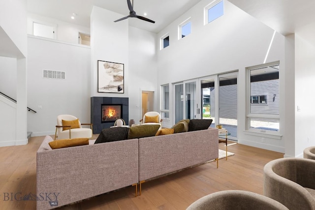 4149 Annie St, Bozeman, MT 59718 - living area featuring a tile fireplace, a ceiling fan, wood finished floors, plenty of natural light, and a towering ceiling