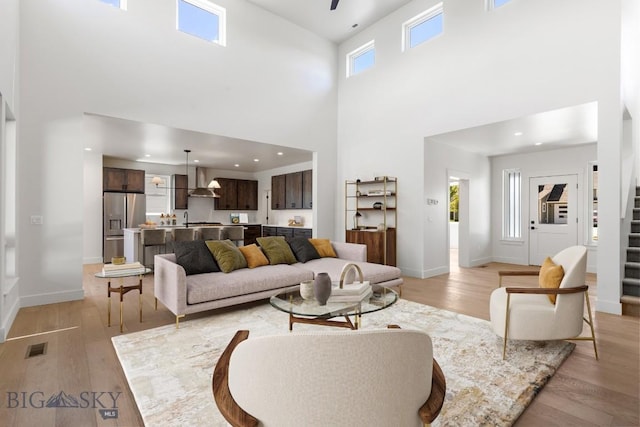 4149 Annie St, Bozeman, MT 59718 - living area featuring light wood-style flooring, a towering ceiling, stairway, baseboards, and recessed lighting