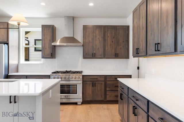 4149 Annie St, Bozeman, MT 59718 - kitchen with wall chimney range hood, appliances with stainless steel finishes, light countertops, light wood-style flooring, and dark brown cabinetry