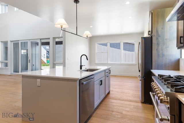 4149 Annie St, Bozeman, MT 59718 - kitchen featuring a sink, appliances with stainless steel finishes, light countertops, light wood-style floors, and an island with sink