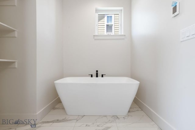 4149 Annie St, Bozeman, MT 59718 - bathroom featuring marble finish floors, baseboards, and a freestanding tub