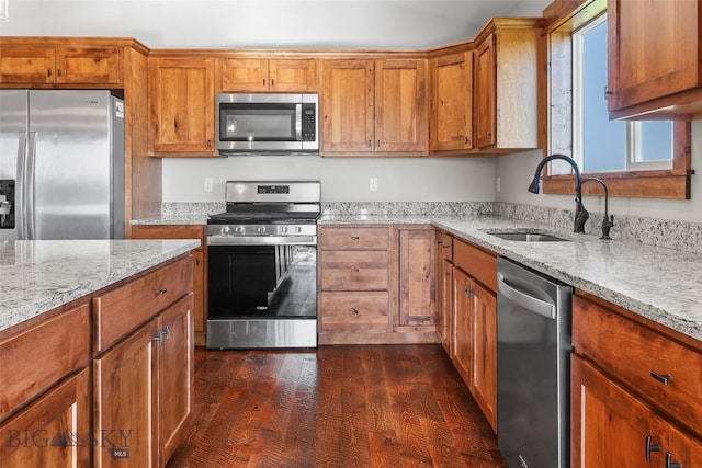 9 Murray Ln, Three Forks, MT 59721 - kitchen featuring stainless steel appliances, brown cabinetry, dark wood-type flooring, and light stone counters