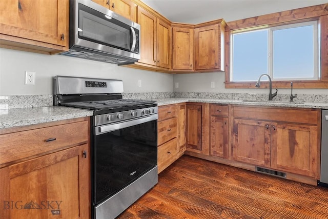 9 Murray Ln, Three Forks, MT 59721 - kitchen with appliances with stainless steel finishes, light stone countertops, brown cabinets, and dark wood-style flooring