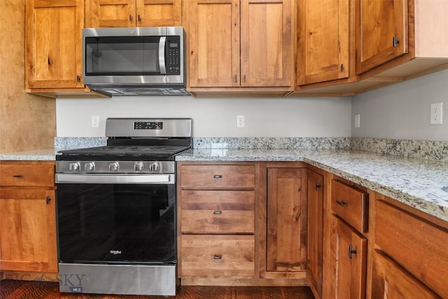 9 Murray Ln, Three Forks, MT 59721 - kitchen with stainless steel appliances, brown cabinetry, and light stone counters
