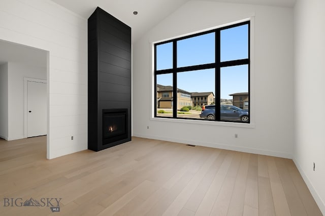286 Lion Peak, Bozeman, MT 59718 - unfurnished living room featuring light wood-style flooring, a large fireplace, and lofted ceiling