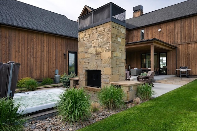 529 Clancy Way, Bozeman, MT 59718 - back of house featuring a shingled roof, a patio, a chimney, stone siding, and an outdoor living space with a fireplace