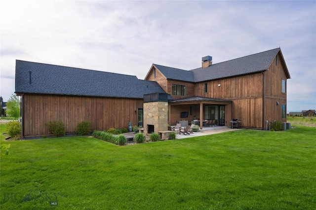 529 Clancy Way, Bozeman, MT 59718 - back of house featuring a patio, a stone fireplace, roof with shingles, a chimney, and a lawn