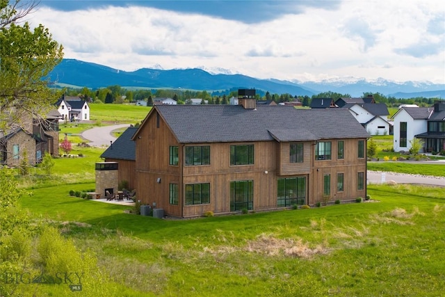 529 Clancy Way, Bozeman, MT 59718 - rear view of house with a mountain view, a shingled roof, a chimney, and a yard