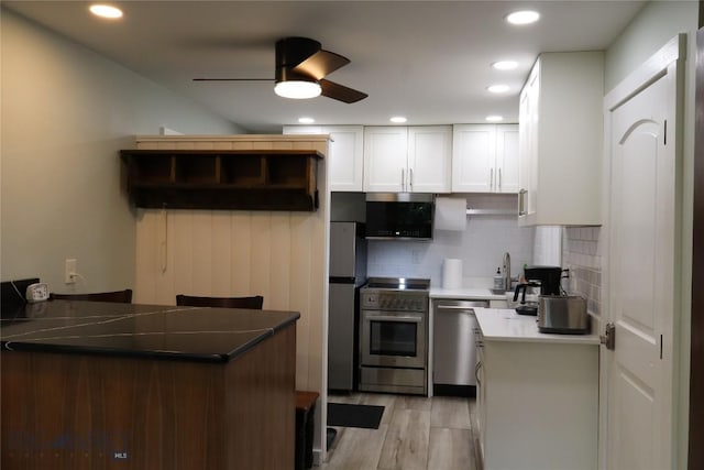 21 Sitting Bull Rd Unit 1190, Big Sky, MT 59716 - kitchen with appliances with stainless steel finishes, ceiling fan, white cabinets, backsplash, and light wood-type flooring