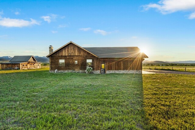 64 Duke Dr, Harrison, MT 59735 - rear view of property featuring a chimney, a lawn, and a mountain view