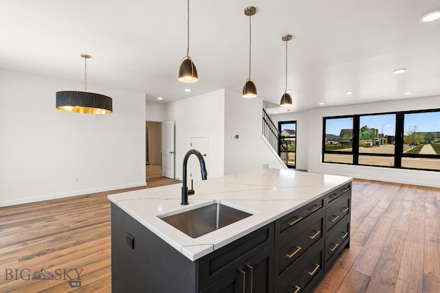 2939 S 30th Ave, Bozeman, MT 59718 - kitchen featuring a sink, wood finished floors, dark cabinetry, light stone counters, and recessed lighting