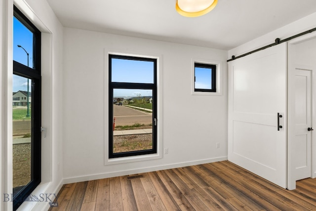 2939 S 30th Ave, Bozeman, MT 59718 - unfurnished room with dark wood-style floors, a barn door, and baseboards