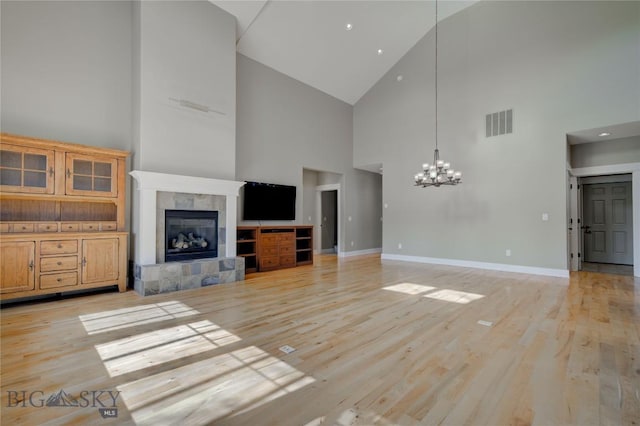 113 Nash Creek Ln, Bozeman, MT 59715 - unfurnished living room with high vaulted ceiling, a fireplace, a chandelier, baseboards, and light wood-type flooring
