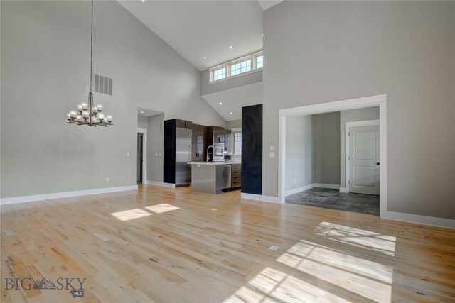 113 Nash Creek Ln, Bozeman, MT 59715 - unfurnished living room with high vaulted ceiling, light wood-type flooring, a chandelier, baseboards, and a sink