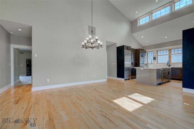 113 Nash Creek Ln, Bozeman, MT 59715 - unfurnished living room featuring high vaulted ceiling, plenty of natural light, light wood-style floors, a chandelier, and baseboards