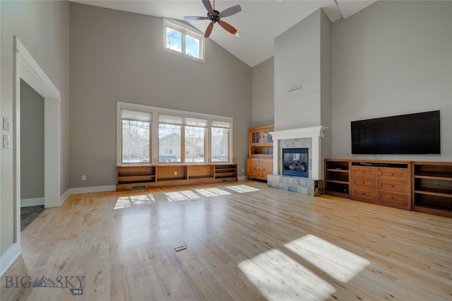 113 Nash Creek Ln, Bozeman, MT 59715 - unfurnished living room featuring high vaulted ceiling, wood finished floors, a ceiling fan, a tiled fireplace, and baseboards