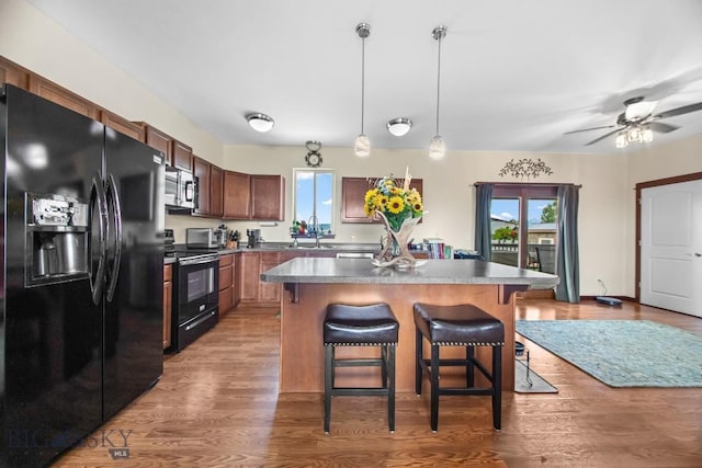 191 Barnes Dr, Belgrade, MT 59714 - kitchen with black appliances, plenty of natural light, a kitchen breakfast bar, and hanging light fixtures