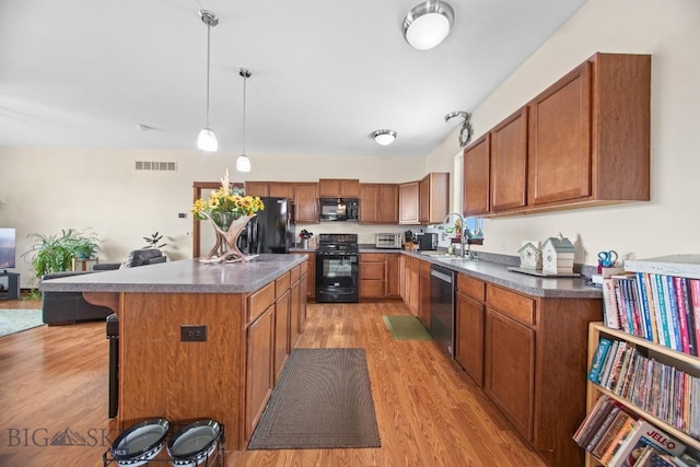 191 Barnes Dr, Belgrade, MT 59714 - kitchen featuring black appliances, light wood-style flooring, a center island, and brown cabinets