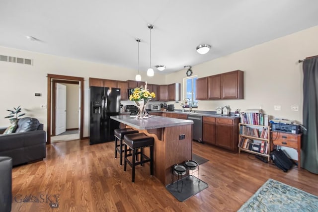 191 Barnes Dr, Belgrade, MT 59714 - kitchen with black fridge with ice dispenser, stainless steel dishwasher, wood finished floors, and a kitchen breakfast bar